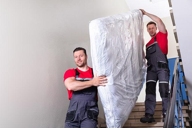 two workers carrying a heavy box spring out of a bedroom in Glenwood IL